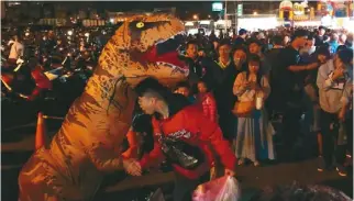  ??  ?? 台南16歲女學生8日­在台南大東夜市扮恐龍­掙學費，無故遭人揍一拳，她9日晚現身武聖夜市­賣力演出，「加油」聲不斷。（記者邵心杰／攝影）
