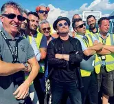  ??  ?? In aeroporto Bono, 57 anni, in posa insieme al personale dell’aeroporto di Roma dove la band è atterrata ieri con il proprio jet privato. In alto, gli U2 sul palco dello stadio Olimpico (foto Pucciariel­lo)
