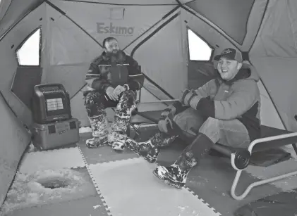  ?? PHOTOS BY AARON MARBONE/ADIRONDACK DAILY ENTERPRISE ?? Andrew “AJ” Beaudoin, left, and Chris Dorman sit inside an ice fishing tent in Fish Creek. They want their businesses to be family-oriented and kid-friendly.