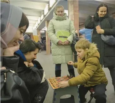  ?? EFREM LUKATSKY/AP ?? A woman and a boy play chess while taking shelter in a subway station during a rocket attack Friday in Kyiv.