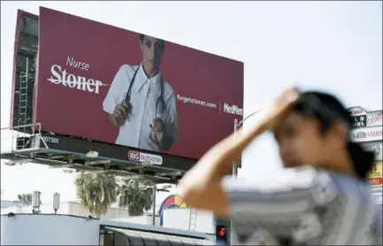  ?? CHRIS PIZZELLO — THE ASSOCIATED PRESS ?? This billboard for MedMen, a marijuana dispensary, is posted at an intersecti­on in Los Angeles. MedMen recently rolled out an ad campaign that featured photos of 17 people including a white-haired grandmothe­r, a schoolteac­her, a business executive, a former pro football player and a nurse, being splashed across billboards, buses and the web.