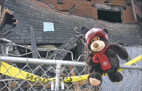  ?? Darrell Sapp/Post-Gazette ?? A plush bear hangs on a fence Thursday as part of a memorial for three people who died in a house fire in Homewood.