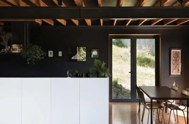  ??  ?? Top The cupboards of the kitchen island have a white lacquered finish. ‘Māori Alphabet’ blocks by Johnson Witehira sit on the rangehood. To the right is a postcard from Aroha &amp; Friends; a painting by Miles Harty; and a lithograph by Marian Maguire.