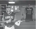  ??  ?? Torey Lovullo stands in the dugout next to a jersey for Sen. John McCain before Sunday’s game against the Seattle Mariners at Chase Field in Phoenix. The six-term Arizona senator died Saturday at age 81.