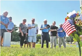  ??  ?? Veterans of the USS Rogers and members of the Rogers family share a moment of silence at the Rogers brothers’ gravesite at the Chattanoog­a National Cemetery.