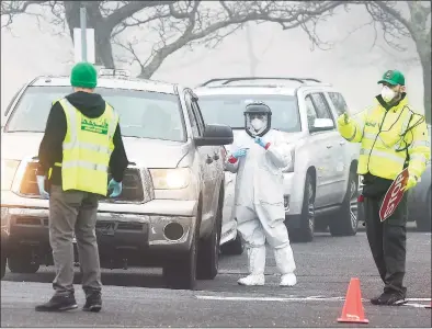  ?? Matthew Brown / Hearst Connecticu­t Media ?? A line of cars wait as medical personnel from Murphy Medical Associates administer drive-thru screenings for the COVID-19 coronaviru­s at a mobile testing site set up at Cummings Beach in Stamford on March 20.