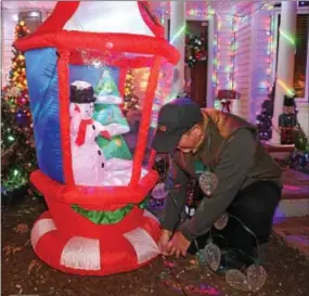  ?? PHOTOS BY PETE BANNAN — DIGITAL FIRST MEDIA ?? Jerry Corrado adjusts one of the hundreds of decoration­s and cords.