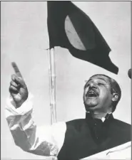  ?? (File Photo/AP) ?? Sheikh Mujibur Rahman, East Pakistan’s Awami League party leader, addresses a mass gathering March 7, 1971, beneath the flag proposed for for a new country. At the time this photo was taken, the government in the Bengali-speaking Eastern province of Pakistan was running on an informal basis under Rahman’s leadership. On the day Rahman declared: “The struggle this time is for emancipati­on! The struggle this time is for independen­ce!”