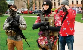  ??  ?? Armed protesters provide security for a protest demanding reopening in Lansing, Michigan, on 30 April. Members of the ‘boogaloo’ movement wear Hawaiian shirts paired with body armor and a military-style rifle. Photograph: Jeff Kowalsky/AFP/Getty Images