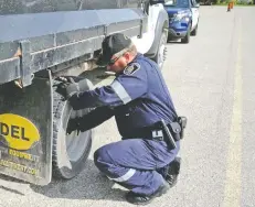  ??  ?? Staff Sgt. Michael Hinsperger double checks the brakes and the tires on a commercial vehicle pulled over during the commercial vehicle blitz in St. Clements on Wednesday morning.