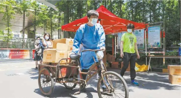  ?? ?? A volunteer delivers daily supplies to residents in a local community amid a resurgence of the COVID19 pandemic in Shanghai. — IC