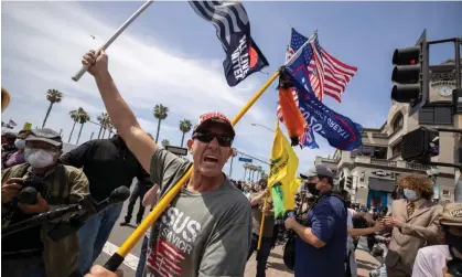  ?? David McNew/Getty Images ?? An evangelica­l Christian carries flags at the site of a ‘White Lives Matter’ rally on 11 April 2021 in Huntington Beach, California. Photograph: