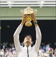  ?? Tim Ireland Associated Press ?? NOVAK DJOKOVIC, not exactly new at this, lifts the Wimbledon men’s trophy after beating Roger Federer.
