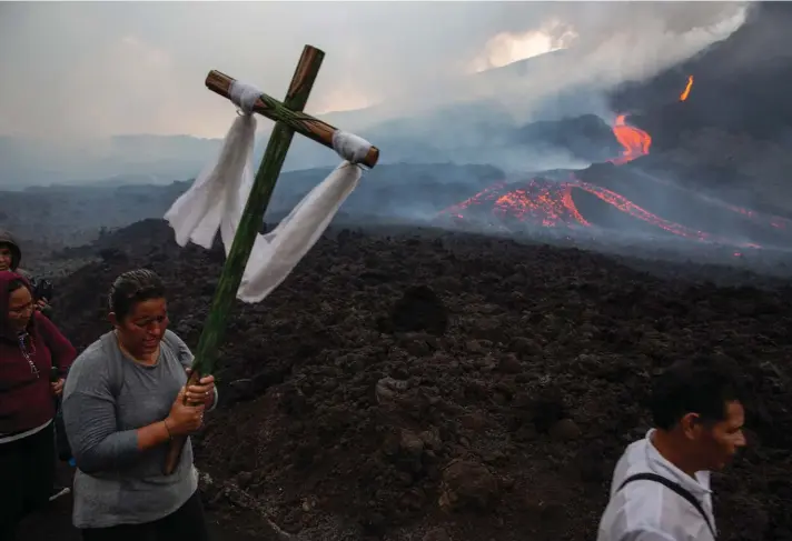  ??  ?? A woman carries a wooden cross during a pilgrimage to pray that the Pacaya volcano decreases its activity, in San Vicente Pacaya, Guatemala, yesterday. The volcano, just 50 kilometres south of Guatemala's capital, has been active since early February. Photo: AP