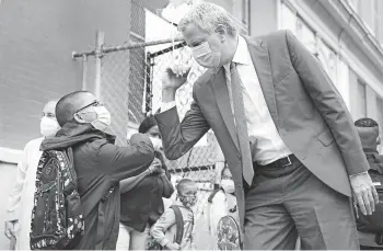  ?? JOHN MINCHILLO/AP ?? Big back-to-school test: New York Mayor Bill de Blasio greets students as they arrive for in-person classes Tuesday at Public School 188 in Manhattan. Hundreds of thousands of elementary school students headed back to classrooms as New York City enters a high-stakes phase of resuming in-person learning during the coronaviru­s pandemic.