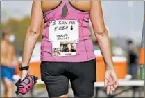  ?? ABEL URIBE/CHICAGO TRIBUNE ?? A woman wears a sign indicating why she is running the virtual Chicago Marathon on Saturday near Belmont Harbor.