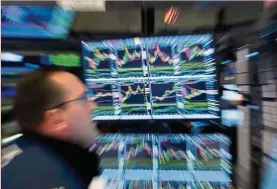  ?? — AFP ?? Market push: A trader walks past a screen at the New York Stock Exchange. The liquidity gush that is keeping markets afloat stems from the stimulus package led by the US.