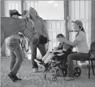  ?? Janelle Jessen/Herald-Leader ?? Physical therapy assistant Holly Harrington (right) works with a patient who has not been cleared to ride by a doctor with the help of side-walker Emily Linn (center) and horse-handler Lori Perdue (left). The horse offers motivation for the patient to practice raising his head to look up and to practice tracking the horse’s movement with his eyes.