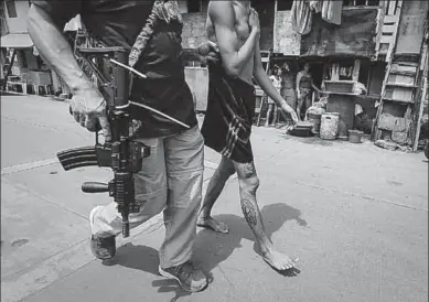  ??  ?? An alleged drug user is arrested at a slum area in Manila, Philippine­s. (Photo: epa)