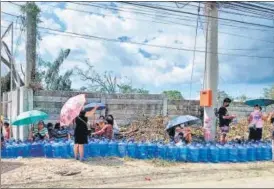  ?? AFP ?? Residents with their water plastic containers queue up to fetch water along a road in Tagbilaran City, Bohol province on Mondays, days after super Typhoon Rai hit the province.