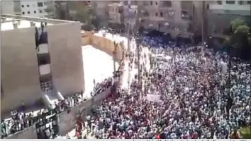  ??  ?? متظاهرون في حي صلاح الدين بحلب وأحدهم يرفع علم الثورة على مدرسة