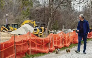  ?? ARVIN TEMKAR/ARVIN.TEMKAR@AJC.COM ?? A man and his dogs stroll past ongoing constructi­on on the Beltline at Piedmont Park in Atlanta. MARTA’s senior engineer said Thursday the transit agency is going ahead with its plans to integrate light rail — specifical­ly streetcars — into the 22-mile loop.