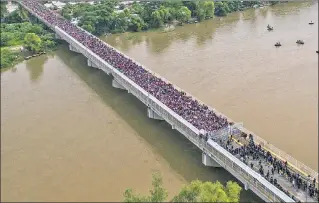  ??  ?? STANDOFF: Thousands of Honduran migrants are met by a fence — and a phalanx of Mexican riot police — as they try to cross a bridge from Guatemala to Mexico on Friday.