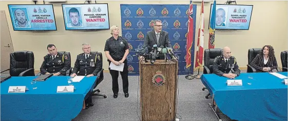 ?? JOHN RENNISON THE HAMILTON SPECTATOR ?? Hamilton Police Detetive Peter Thom, centre, speaks at a Thursday press conference announcing an arrest in the Angelo Musitano and Mila Barberi murders. Shown behind him are photos of one suspect in custody and the two others still being sought.