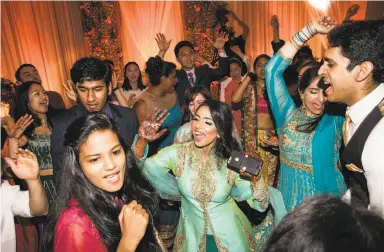  ?? Photos by Laura Morton / Special to The Chronicle ?? Bride (center) and groom (right) cut loose on the dance floor with wedding guests during their reception.