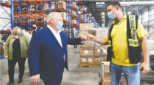  ?? Nathan Denette / THE CANADIAN PRESS ?? Ontario Premier Doug Ford, left, fist-bumps an employee as he tours a warehouse in Milton on Wednesday. Ford has not been nearly so confident about the state of the coronaviru­s in recent weeks, Randall Denley writes.