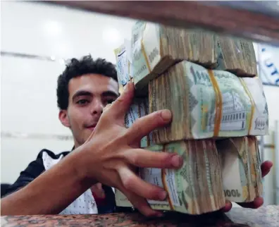  ?? Reuters/File ?? A money-changer holds bundles of Yemeni currency at an exchange shop in Sanaa, Yemen.