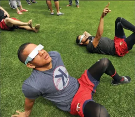  ?? PAUL BEATY — THE ASSOCIATED PRESS ?? Minnesota Twins players Ehire Adrianza front, and Ervin Santana back, along with other members of the team watch the solar eclipse before a baseball game against the Chicago White Sox Monday in Chicago.