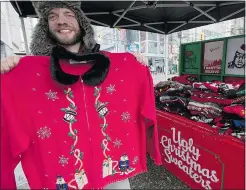  ?? — THE CANADIAN PRESS FILES ?? Stephen Peever holds up an ugly Christmas sweater on Granville Street in downtown Vancouver on Friday. He can sell up to 30 of them on a good day