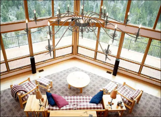  ??  ?? The home’s living room is large and features floor-to-ceiling windows to catch the sweeping mountain views.