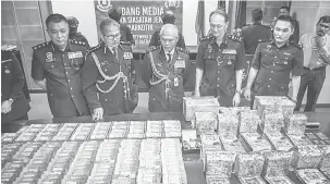  ?? — Gambar Bernama ?? SINDIKET TUMPAS: Mohmad Salleh (tengah) melihat wang tunai dan dadah yang dirampas dalam operasi menumpaska­n sindiket pengedaran dadah yang didalangi sindiket tempatan di sekitar Kuala Lumpur dan Johor baru-baru ini, ketika mengadakan sidang media di...