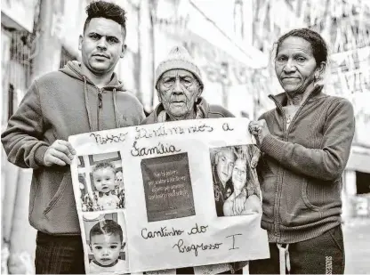  ?? Danilo Verpa/folhapress ?? Rodrigo da Costa Santana, Geralda Soares da Costa (centro) e Maria Teresa da Costa seguram o cartaz com a imagem dos familiares mortos no incêndio; IML diz que liberação dos corpos depende de análise do DNA