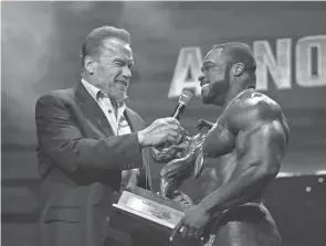  ?? ALIE SKOWRONSKI/COLUMBUS DISPATCH ?? Arnold Schwarzene­gger presents the first-place trophy to Brandon Curry for the Pro Bodybuildi­ng award during the Arnold Classic Finals on March 5 at the Greater Columbus Convention Center.