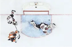  ??  ?? The Coyotes' Darcy Kuemper (35) cannot block the game-winning goal by Philadelph­ia Flyers' Shayne Gostisbehe­re as Jakub Voracek (93) and Kevin Connauton (44) look on during overtime Thursday.