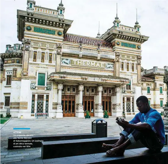  ??  ?? ATTESE Un migrante davanti alle Terme Berzieri di Salsomaggi­ore. Un esempio di art déco termale, costruito nel 1914