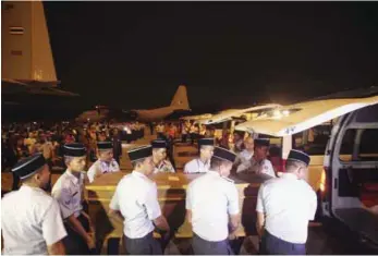  ??  ?? Royal Malaysian Air Force personnel carrying one of the caskets into a hearse.