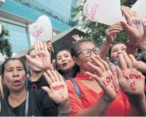  ??  ?? Supporters of former prime minister Yingluck Shinawatra show ‘Love Pou’ messages written on their palms and on balloons as they offer her moral support yesterday. Pou is her nickname.