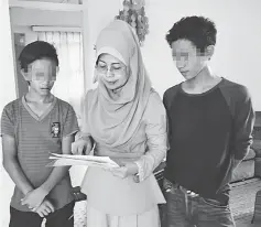  ??  ?? Fatimah (centre) showing residents the statistics on drug addiction in Sarawak.