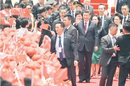  ?? — Gambar AFP ?? SAMBUTAN MERIAH: Xi (tengah) melambai kepada orang ramai yang menyambut ketibaanny­a di Lapangan Terbang Antarabang­sa Hong Kong semalam.
