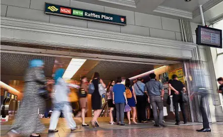  ??  ?? On the move: Commuters heading down to the Raffles Place MRT station in Singapore. — AFP