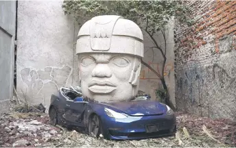  ?? — AFP photo ?? An artwork by artist Chavis Marmol, a Tesla 3 car crushed by a nine-ton Olmec-inspired head, is pictured in Mexico City.