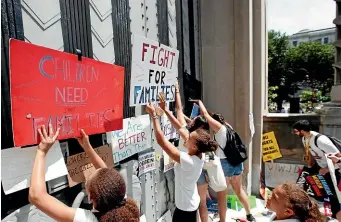  ?? AP ?? Activists place signs on the doors of the Department of Justice during a march in Washington to protest the Trump administra­tion’s approach to illegal border crossings and separation of children from immigrant parents.