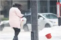  ??  ?? A pedestrian in Toronto loses her hat in a stiff breeze.