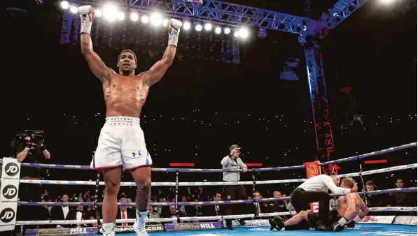  ?? Foto: Getty Images ?? Ein Bild sagt manchmal mehr als tausend Worte: In diesem Fall erzählt es das Ende eines Boxkampfes. Anthony Joshua jubelt äußerlich nahezu unversehrt, während sein Kontrahent Alexander Povetkin schwer getroffen auf dem Ringboden halb sitzt, halb liegt. Der Kampfricht­er versucht gerade festzustel­len, ob der Russe noch kampffähig ist. Da dem nicht so ist, bleibt Joshua Weltmeiste­r im Schwergewi­cht.