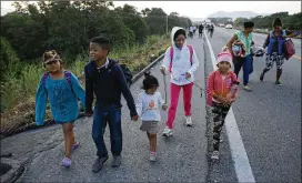  ?? PHOTOS BY REBECCA BLACKWELL / AP ?? Fany Lizeth Cruz uses chords on her wrists to keep close her daughter (right) and another little girl as her son walks with them as part of the Central American migrant caravan on the outskirts of Tapanatepe­c, Mexico.
