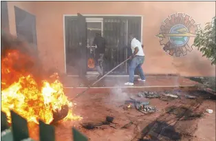  ?? ODELYN JOSEPH - THE ASSOCIATED PRESS ?? Workers put down a fire set at an office of Haiti’s power company during a protest to demand the resignatio­n of the Prime Minister Ariel Henry in Port-au-Prince last Friday.